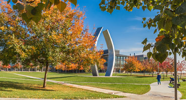 Photo of campus during fall with Beginnings statue feature.